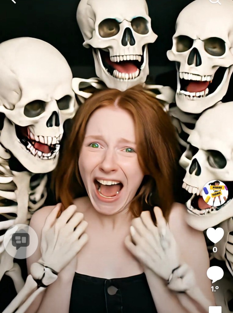 A ruiva está aconpanhada de várias caveiras brancas num fundo preto atormentando a ruiva? Ela não aparece atormentada não!
